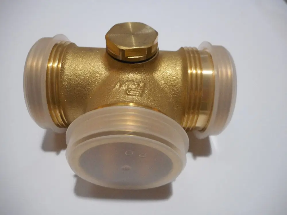 T-Stück aus Messing mit zwei transparenten Kunststoffanschlüssen und einem Deckel. Produkt von Remeha, geeignet für Rohrverbindungen in Heizungs- oder Sanitärinstallationen.